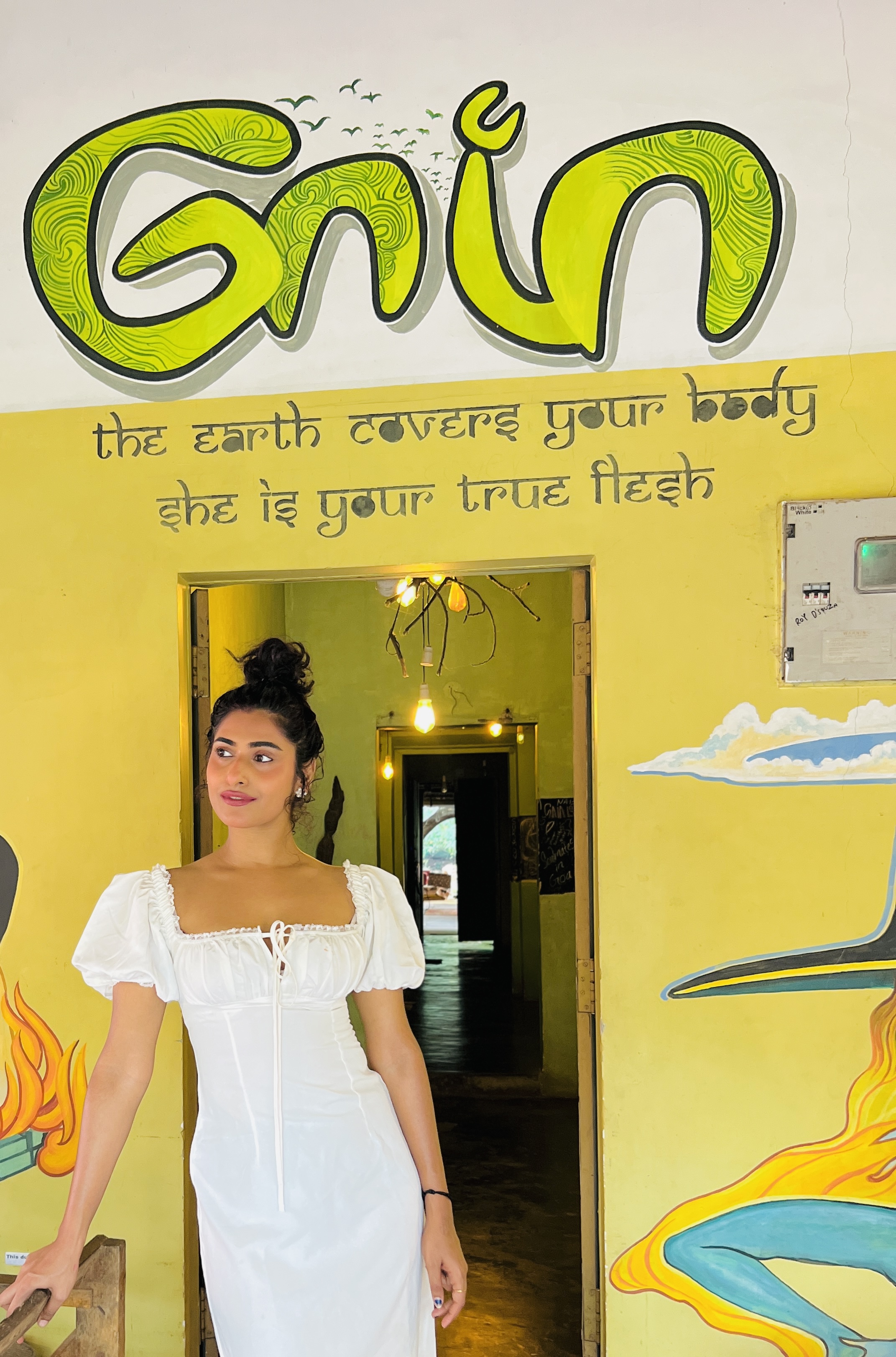 Sharo Philip — founder of Home of Gaia, standing under the Gaia mural in Morjim